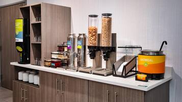 Een ontbijtbuffet met verschillende automaten voor eten, waaronder een koffieapparaat, melk, ontbijtgranen en havermout.
