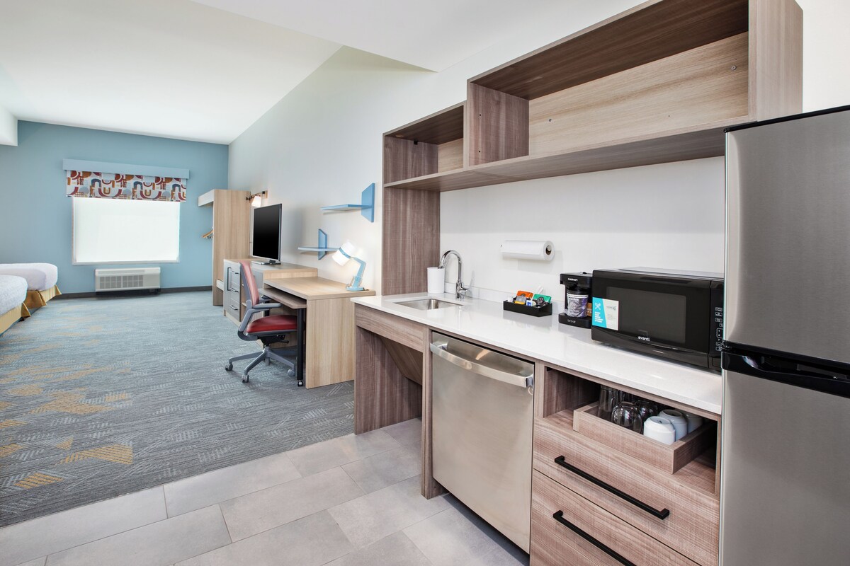 Eine moderne Küche mit Edelstahl-Kühlschrank, Mikrowelle und Geschirrspüler. Es gibt eine Holz Arbeitsplatte und ein eingebautes Spülbecken.