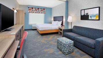Ein modernes Hotelzimmer mit Bett, Sofa, Fernseher und Schreibtisch.