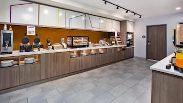 Eine moderne Frühstücksbar mit einer Kühltheke, einer Kaffeemaschine und einer Auswahl an Frühstücksangeboten.