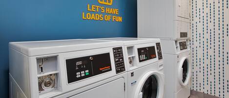 A laundry area with multiple washing machines and a wall with a motivational quote.