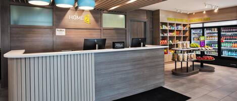 Et hotellets receptionsområde med et moderne design, inklusive en receptionsdisk, computere og en snackbar.