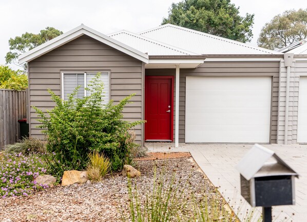 A residential house with a red door, grey siding, and a white garage door. - Villa Marlee | Margaret River (Margaret River)