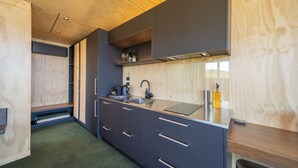 A modern kitchen with dark cabinets, a stainless steel sink, and a wooden countertop. - Tukare Lookout (Te Anau)