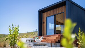 A modern building with large glass windows, a wooden deck, and a gravel ground. - Tukare Lookout (Te Anau)