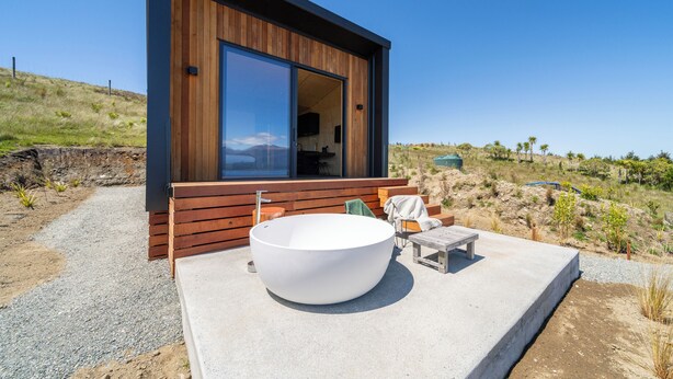 A modern building with a large window, a concrete platform, and a large white bathtub. - Tukare Lookout (Te Anau)