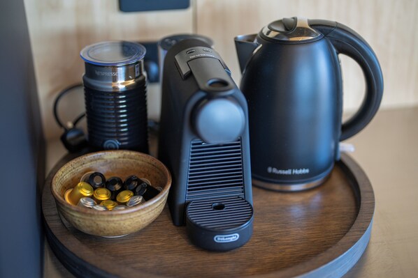 A wooden tray with a black electric kettle, a Nespresso coffee machine, and a bowl of coffee capsules. - Tukare Lookout (Te Anau)