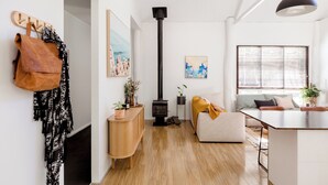 A modern living room with a wooden floor, a sofa, a coffee table, a fireplace, and a hanging coat rack.