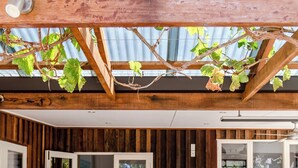 A covered patio with wooden beams and a metal roof, a wooden table with chairs, and a bench.