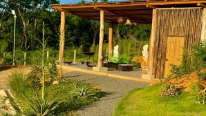 A covered outdoor seating area with a pergola, a barbecue grill, and a bamboo wall. - Essence of Honey Villas & Safari Boutique - Villa # 1 (Provincia de Guanacaste)