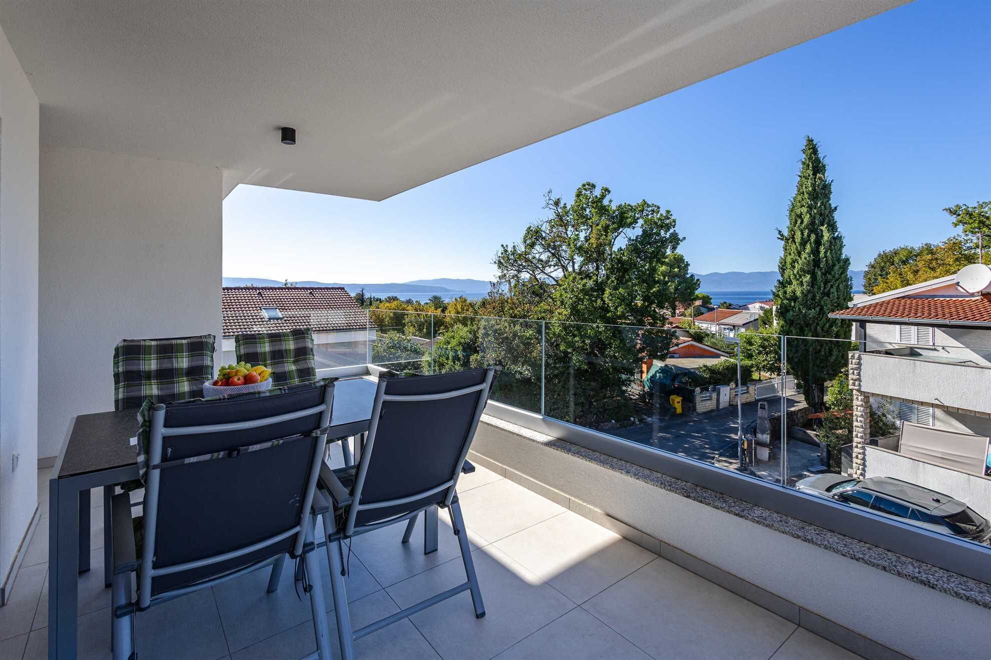 Un balcón con mesa y sillas, con vistas a una zona residencial con casas y árboles.