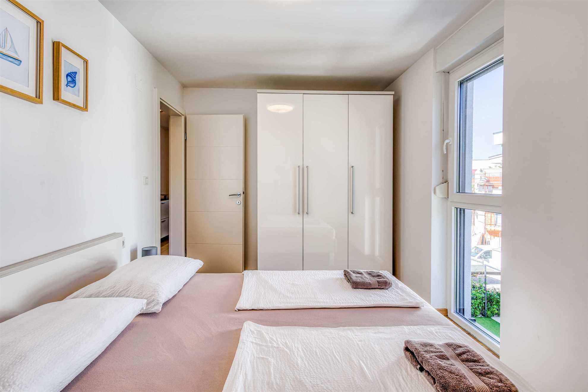 A bedroom with two beds, a wardrobe, and a window with a view.