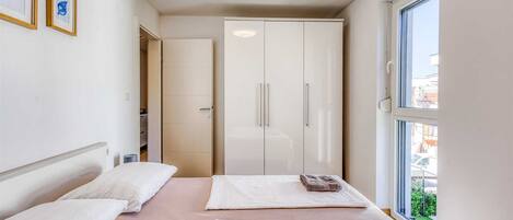 A bedroom with two beds, a wardrobe, and a window with a view.