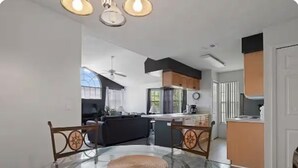 A modern kitchen with a central island, a dining area with a glass table, and a ceiling fan. - condo2/2 pretty Close to Disney (Kissimmee)