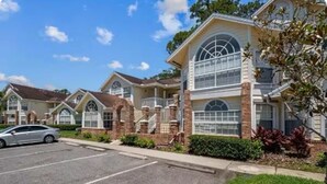 A row of townhouses with large windows and brick facades, a parking lot, and a clear sky. - condo2/2 pretty Close to Disney (Kissimmee)