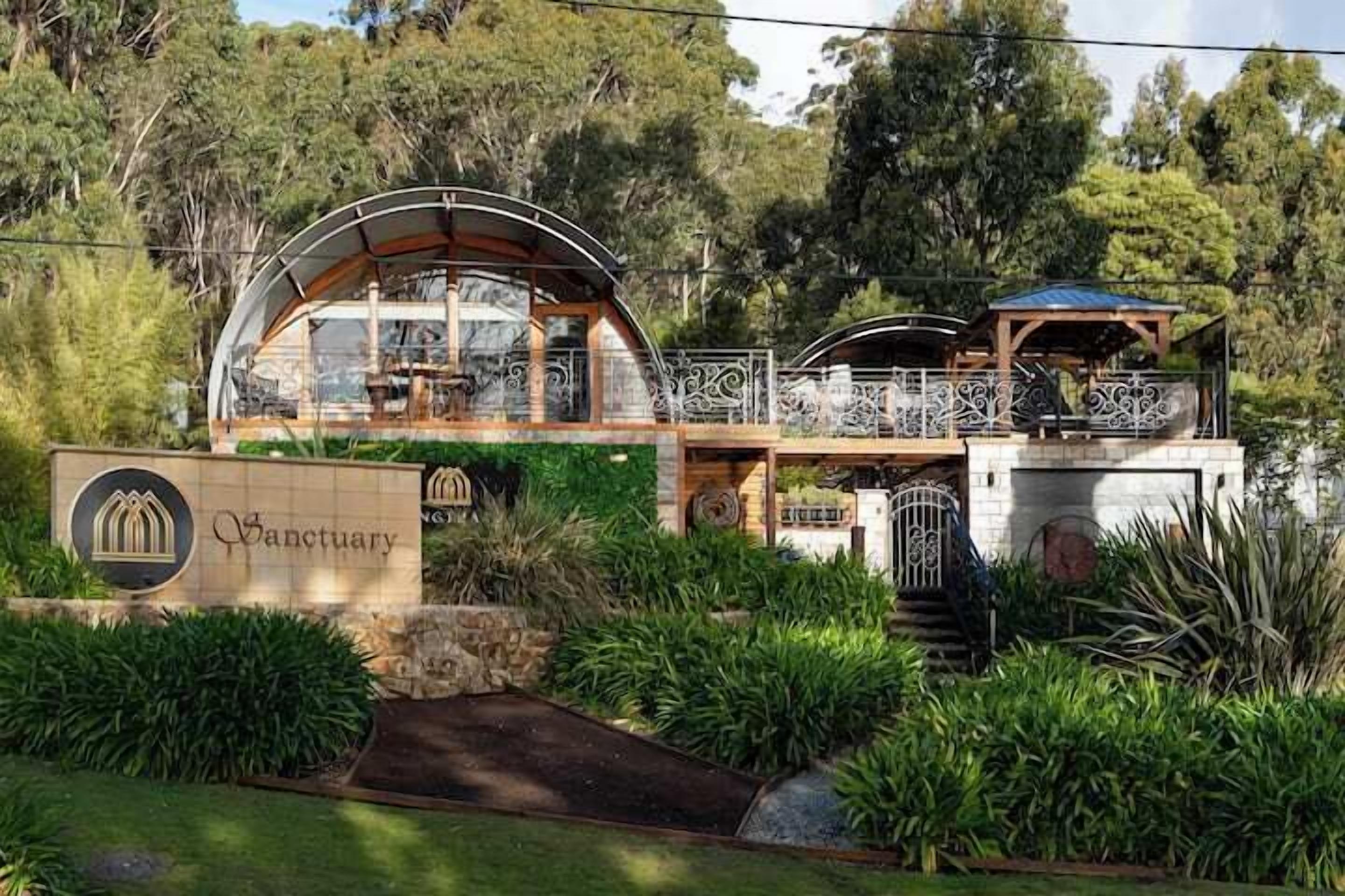 A building with a sign reading "Sanctuary" and a covered outdoor area with a railing.