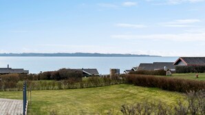 A residential area with houses, a grassy field, and a body of water in the background. - Awesome home in Ebberup with WiFi (Ebberup)