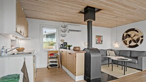 A modern kitchen with a central island, a built-in stove, and a dining area with a gray sofa and a small table. - Awesome home in Ebberup with WiFi (Ebberup)