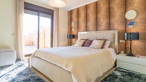 Quarto com uma cama grande, duas luminárias de cabeceira, mesa de cabeceira, espelho e vista para o exterior.
