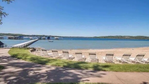 A beach with lounge chairs and a pier with boats. - Creekside Condo w/ Pool & Beach Club #118 (Bellaire)