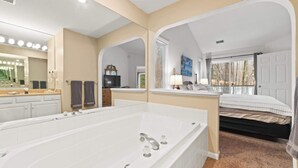 A modern bathroom with a large bathtub, a vanity with a mirror, and a separate shower area. - Creekside Condo w/ Pool & Beach Club #118 (Bellaire)
