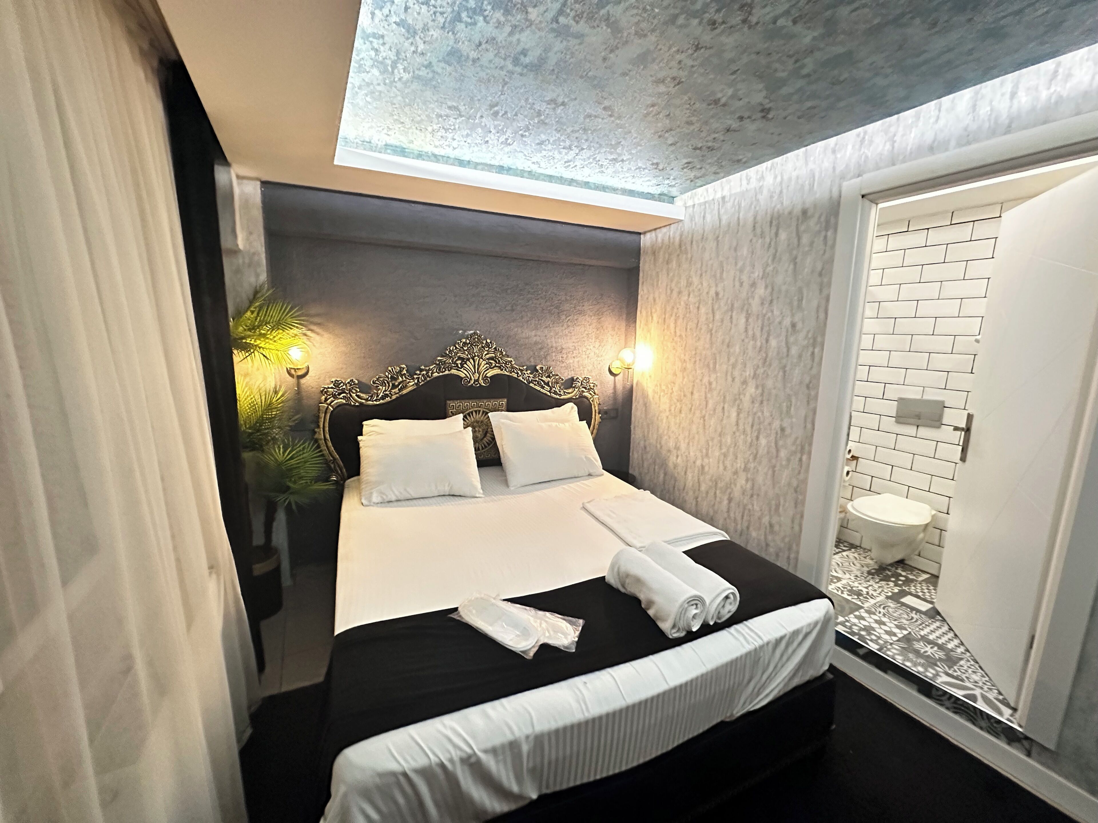 Habitación de hotel con cama, baño y vista al cielo a través de un tragaluz.