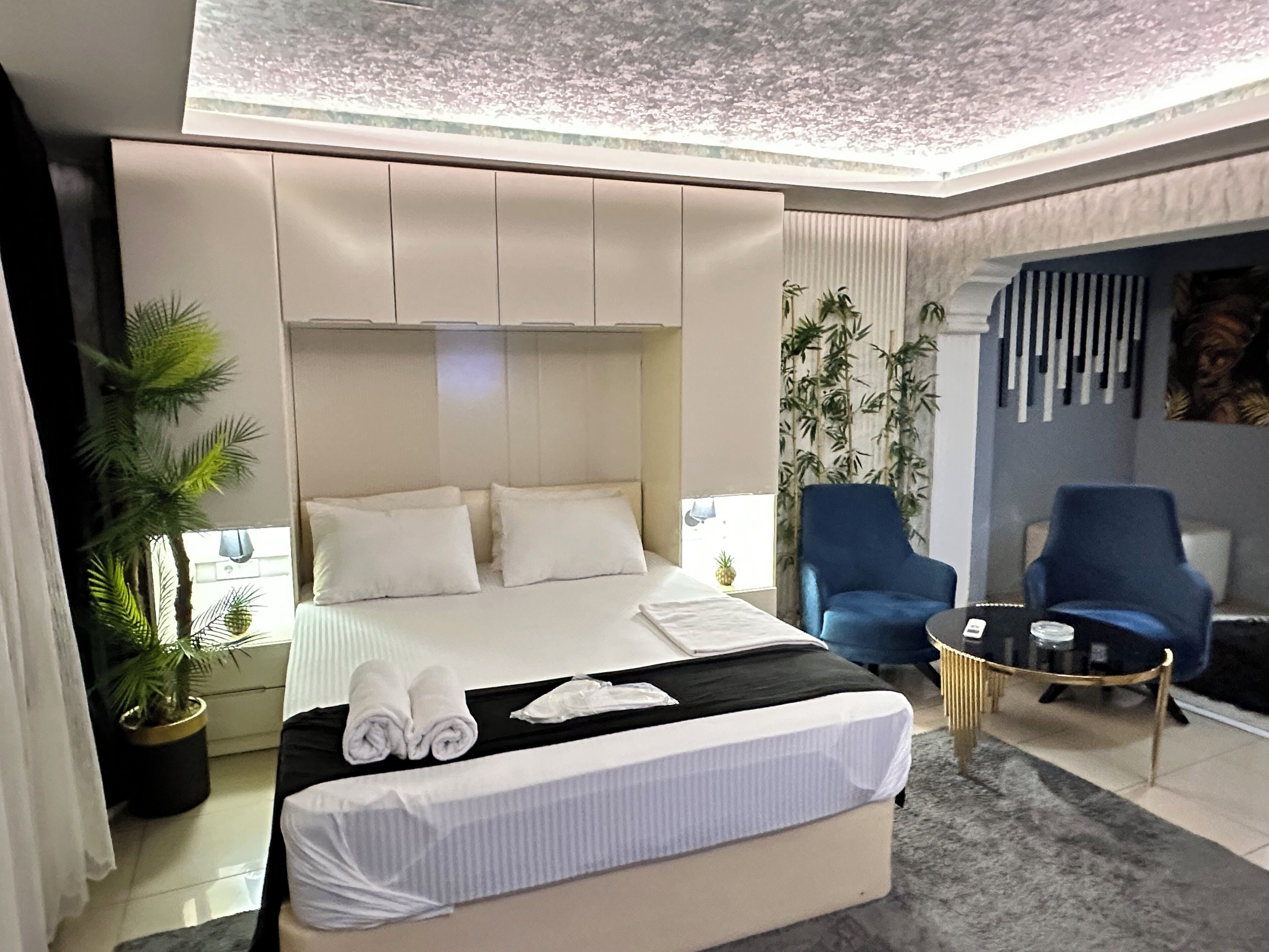 A modern hotel room with a large bed, a seating area, and a view of the outdoors.