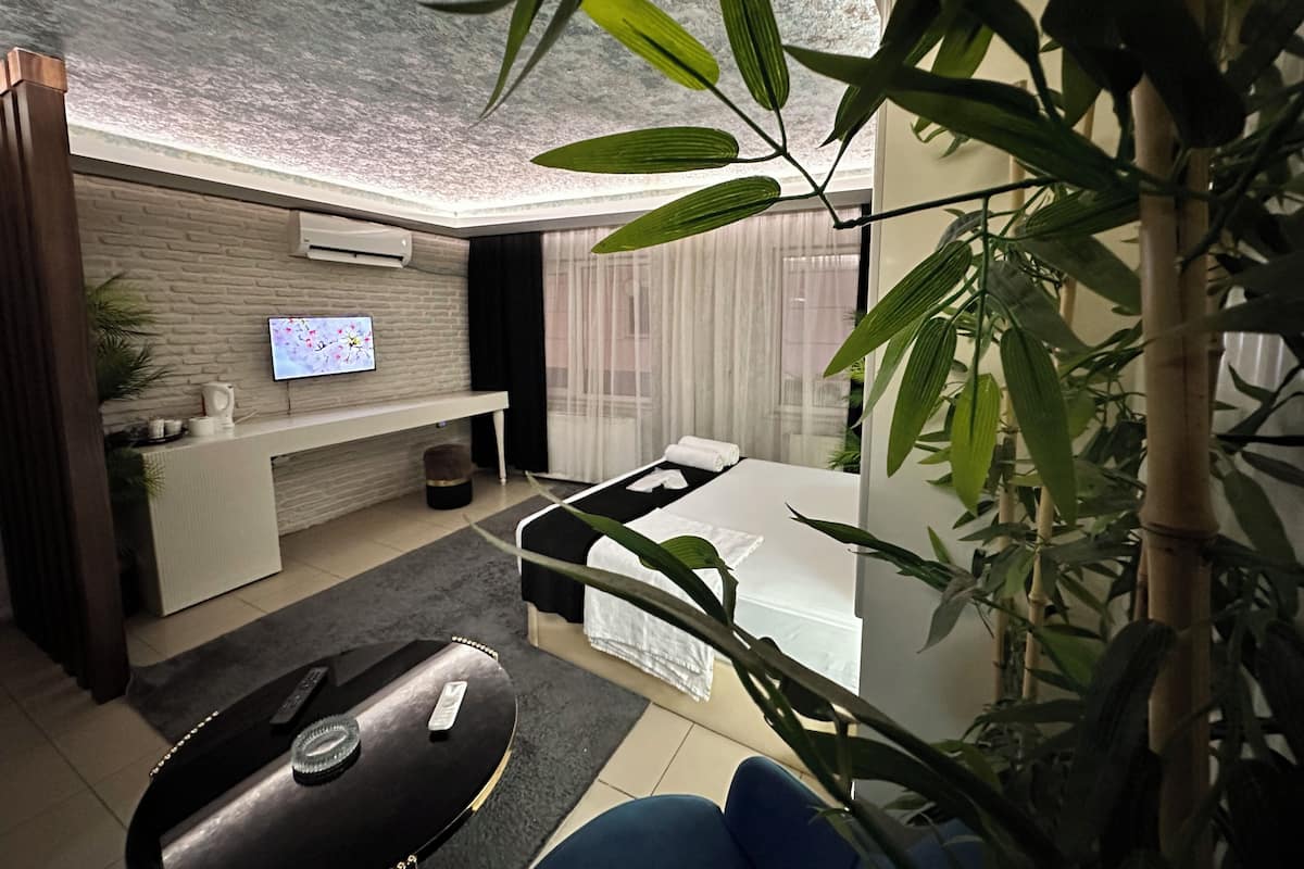 A modern living room with a flat-screen TV mounted on a brick wall, a sofa, a coffee table, and a dining table with a white tablecloth.