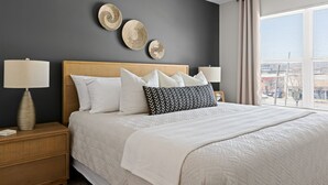 Une chambre à coucher bien aménagée, avec un grand lit, deux tables de chevet et une vue sur la ville par la fenêtre.