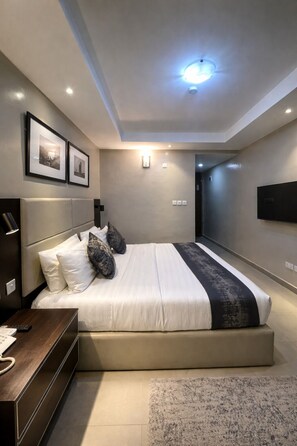 Un dormitorio moderno con una cama grande, mesitas de noche, un televisor de pantalla plana y cuadros en la pared.