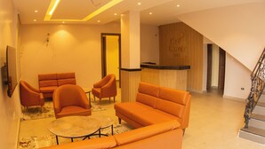 A hotel lobby with orange sofas, a reception desk, and a staircase. - Five Clover Inn Abijo (Lekki)