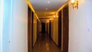 A long, narrow hotel corridor with doors on both sides, recessed lighting, and a polished floor. - Five Clover Inn Abijo (Lekki)
