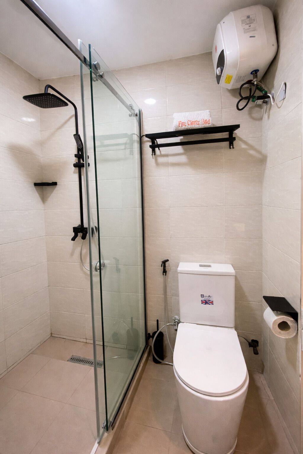 A bathroom with a glass-enclosed shower, a toilet, a towel rack, and a hand dryer.