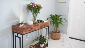 Una consola de madera con un modelo de velero, un florero y una planta en maceta.