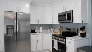 Una cocina moderna con electrodomésticos de acero inoxidable, armarios blancos y un microondas sobre la estufa.