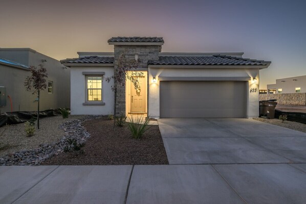 A modern two-story house with a stone facade, a garage, and a landscaped front yard.