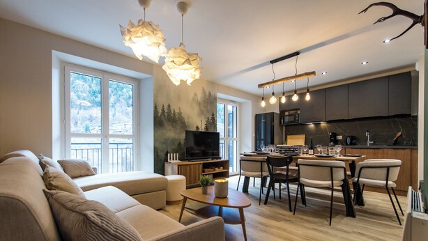 A modern living room with a sofa, dining table, and chairs. There is a TV and a fireplace. - ☆☆☆ 3 Vallées & cycling – Cosy 6 to 8 in the Alps (Orelle)