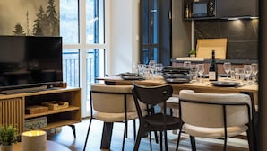 A modern kitchen with a dining area, wooden cabinets, a built-in oven, and a large window. - ☆☆☆ 3 Vallées & cycling – Cosy 6 to 8 in the Alps (Orelle)