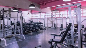 A gym with weightlifting equipment, benches, and dumbbells.