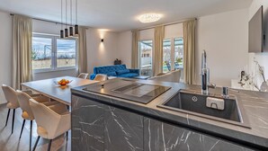 Une cuisine moderne dotée d’un îlot en marbre, d’un évier intégré et de luminaires suspendus.