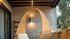 Uma cadeira suspensa com assento e encosto acolchoados, pendurada no teto com um design trançado.