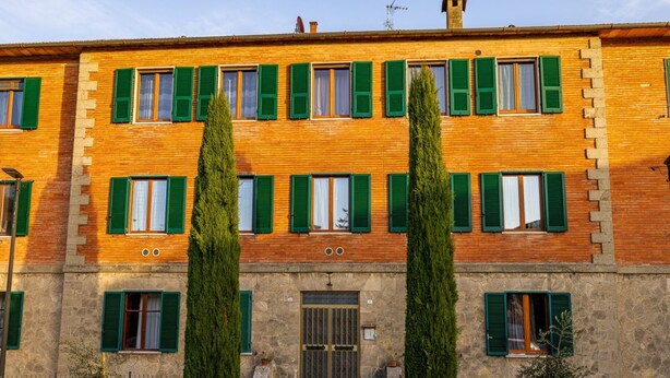 Un immeuble à plusieurs étages, doté de volets verts, d’une entrée en pierre et d’une porte centrale.