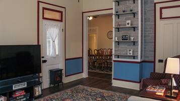 Un salon avec un téléviseur, une bibliothèque et un tapis à motifs.