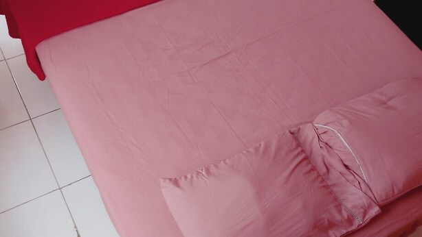 Una cama con cabecera roja y colchón rosa.