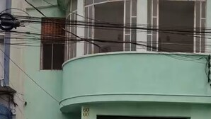 Un edificio con fachada curva, una puerta verde y un SUV estacionado.