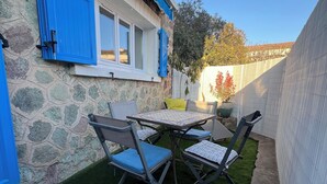 Un patio con mesa y sillas, un muro de piedra y una puerta azul.