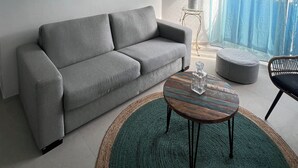 Una sala de estar moderna con un sofá gris, una mesa de centro redonda y una alfombra verde.
