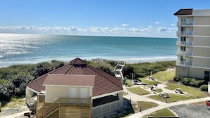 Une propriété située en bord de mer, comprenant une maison en bois, un patio couvert et une vue sur l’océan.