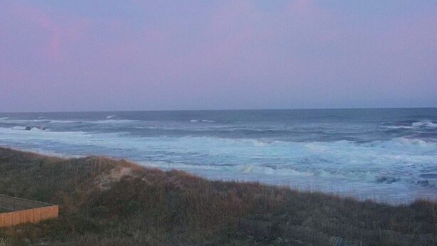 Vista costera con olas y una estructura de madera al frente.