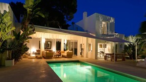 Een modern huis met een zwembad, buitenzitplaatsen en een overdekt terras.